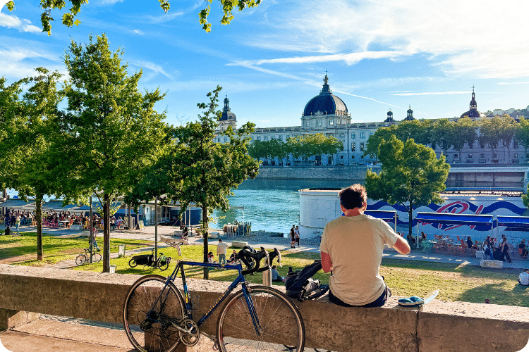 Visiter Lyon à vélo : pause sur les berges du Rhône face au dôme de l'Hôtel-Dieu