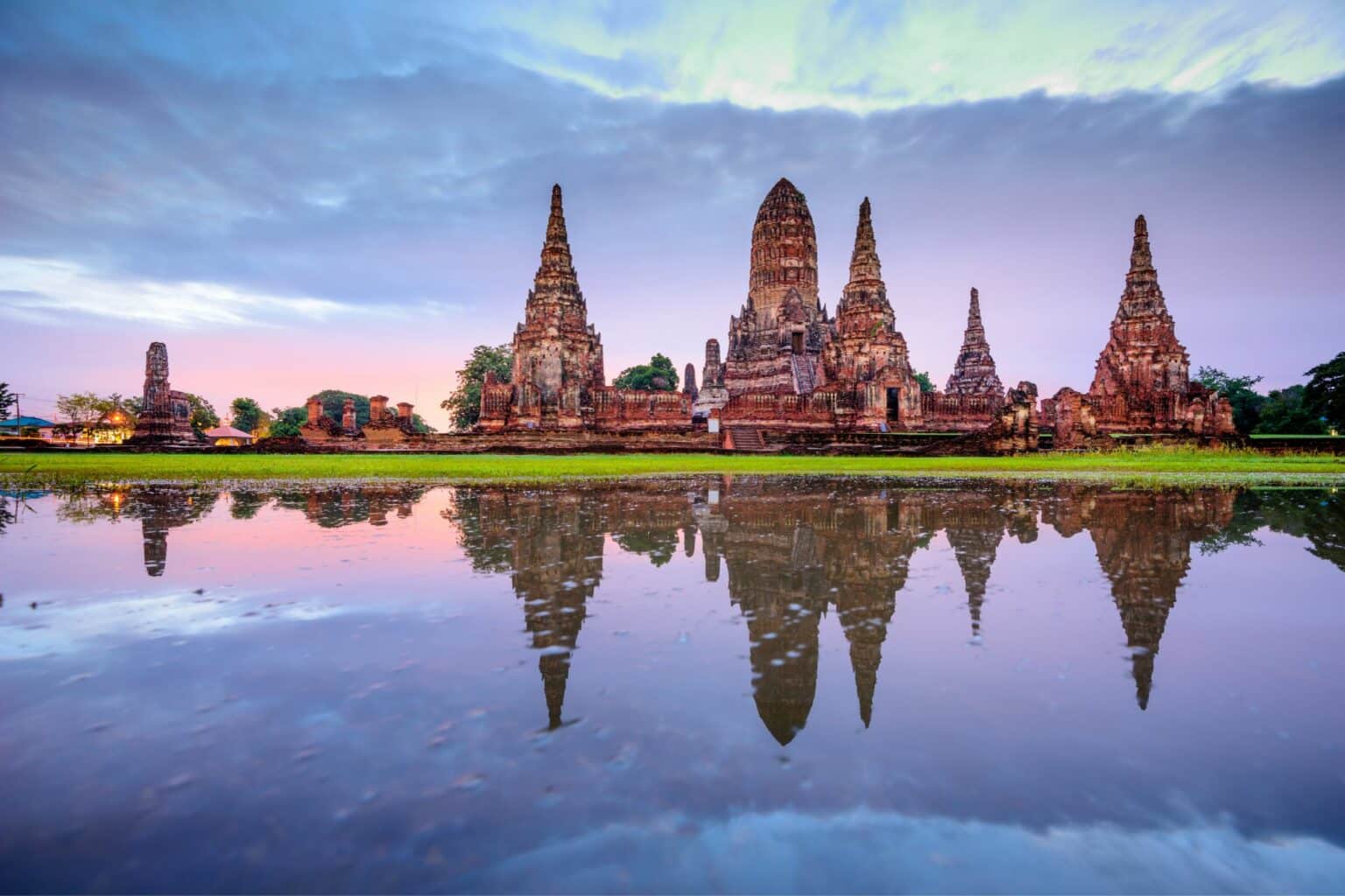 Circuit en Thaïlande : des expériences authentiques Vue sur le temple d'Ayutthaya avec en premier plan une étendue d'eau avec le ciel qui se lève dans des tons indigo